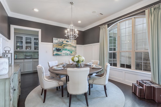 dining space with a decorative wall, a notable chandelier, and dark wood-type flooring