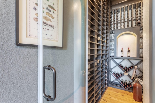 wine area with wood finished floors and a textured wall