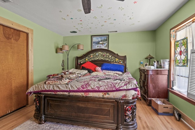 bedroom with visible vents, multiple windows, and wood finished floors