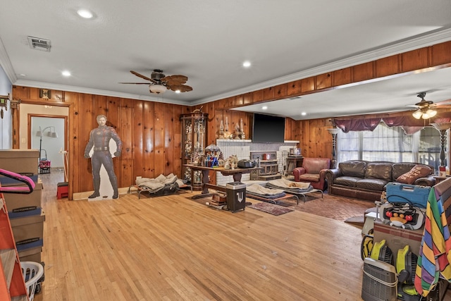 living room featuring visible vents, crown molding, ceiling fan, and wood finished floors