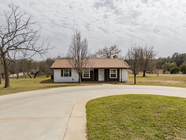 ranch-style house featuring driveway, brick siding, and a front lawn