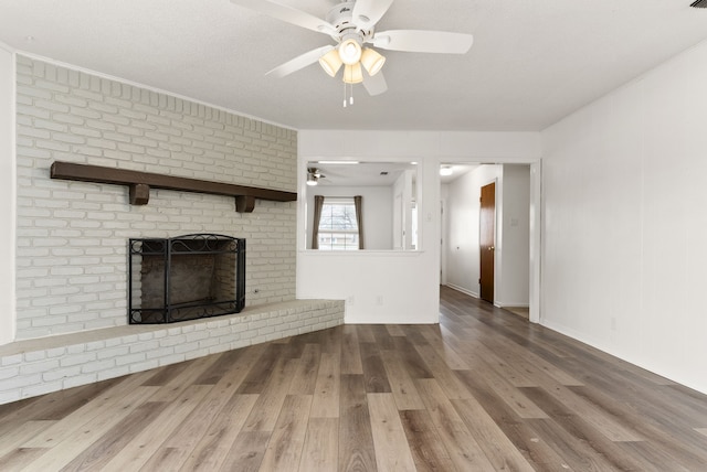 unfurnished living room with wood finished floors, crown molding, a fireplace, and ceiling fan