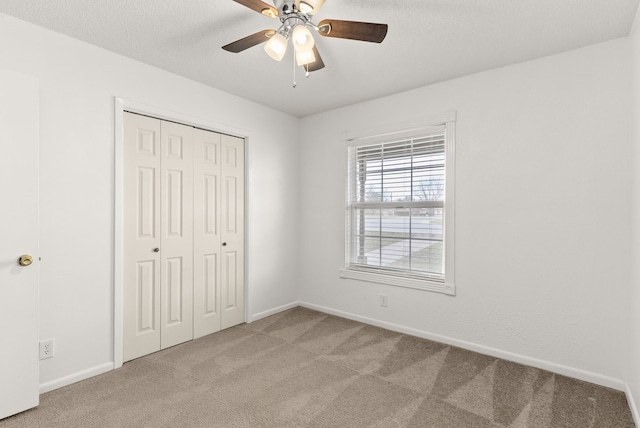 unfurnished bedroom with a closet, light colored carpet, a ceiling fan, and baseboards