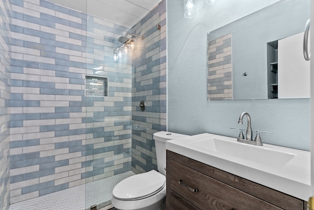 full bathroom featuring a textured wall, toilet, vanity, and a tile shower