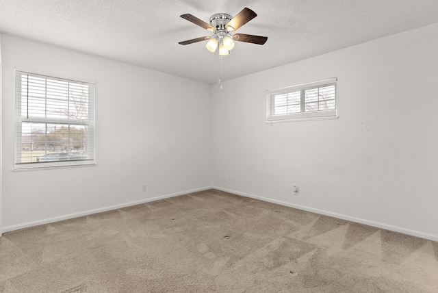 unfurnished room with carpet flooring, a textured ceiling, baseboards, and a ceiling fan