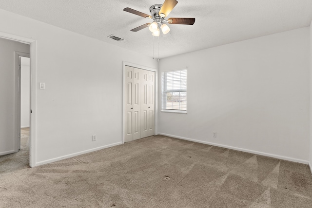 unfurnished bedroom featuring baseboards, visible vents, carpet floors, a closet, and a textured ceiling