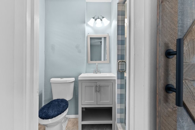 bathroom with vanity, toilet, baseboards, and a stall shower