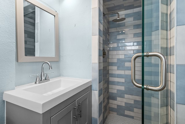 full bath featuring vanity, a shower stall, and a textured wall