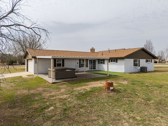 rear view of property with brick siding, a lawn, a hot tub, and a patio