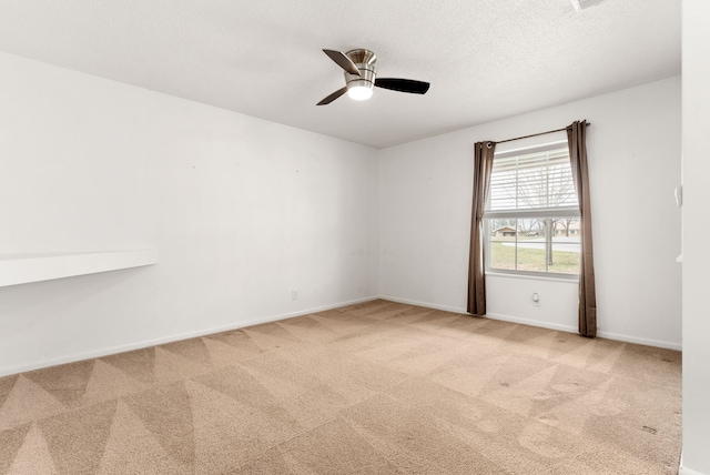 carpeted spare room with a ceiling fan, baseboards, and a textured ceiling