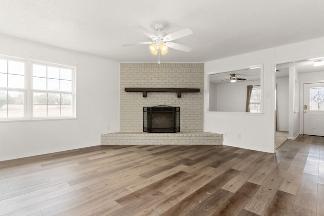 unfurnished living room featuring a wealth of natural light, a brick fireplace, and hardwood / wood-style flooring