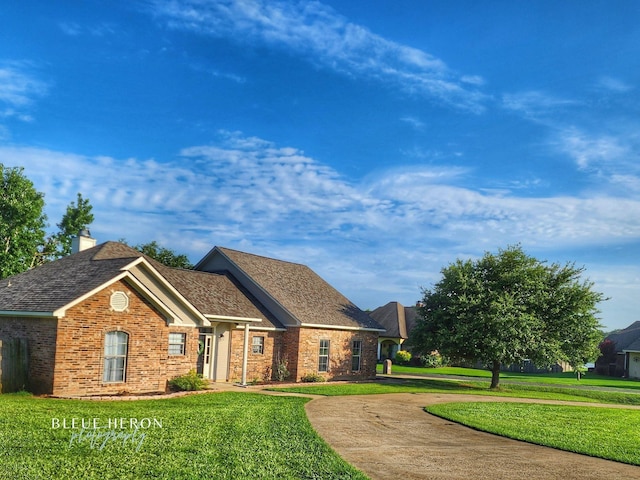 view of front of property featuring brick siding, a chimney, and a front lawn