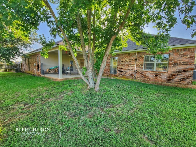 back of house with a patio, fence, a yard, a shingled roof, and brick siding