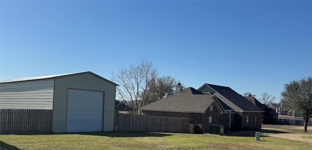 view of home's exterior with an outdoor structure, a lawn, fence, and a detached garage