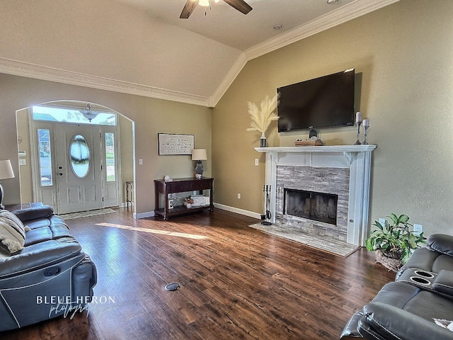 living room with ornamental molding, wood finished floors, a stone fireplace, baseboards, and vaulted ceiling