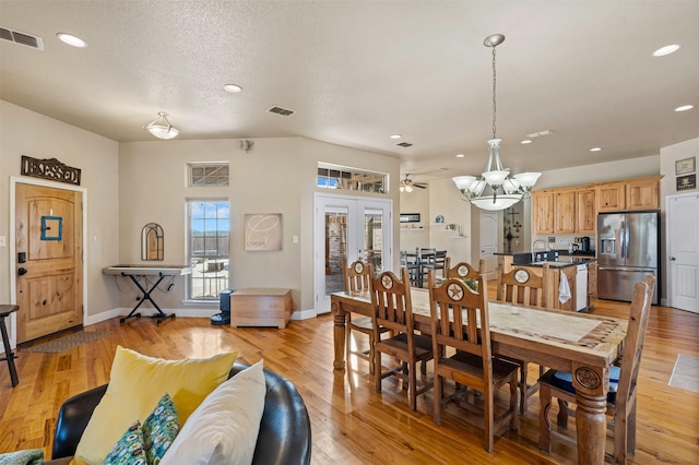 dining area featuring baseboards, visible vents, light wood finished floors, and a chandelier