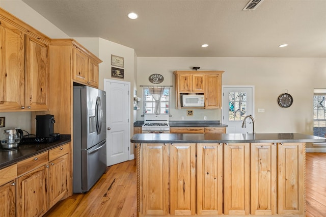 kitchen with visible vents, white appliances, dark countertops, and plenty of natural light