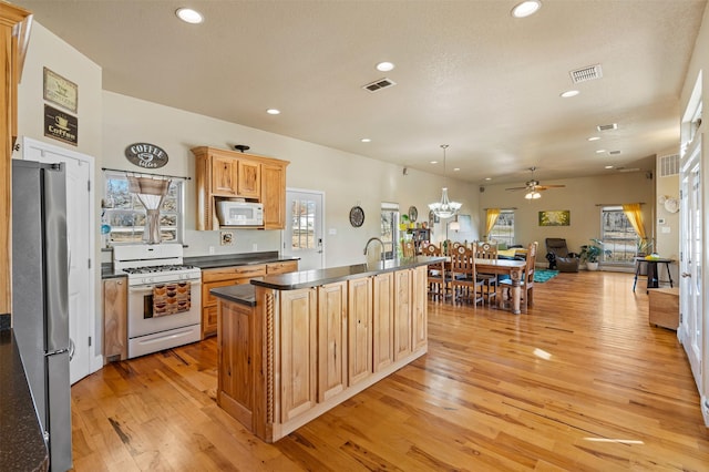 kitchen with dark countertops, visible vents, white appliances, and open floor plan