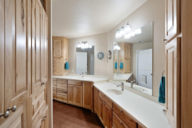 full bath with a textured ceiling, two vanities, a textured wall, and a sink