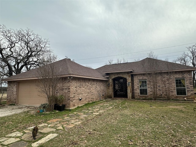 view of front of property featuring brick siding, a shingled roof, a front lawn, a garage, and driveway