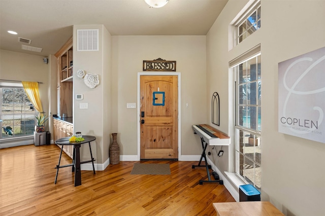 foyer with recessed lighting, visible vents, baseboards, and wood finished floors