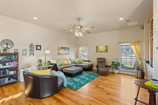 living area with visible vents, plenty of natural light, wood finished floors, and a ceiling fan