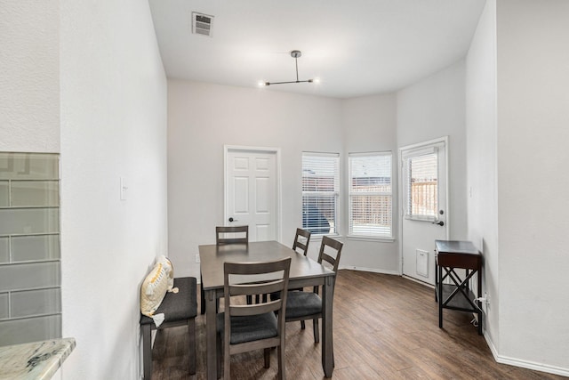 dining area with dark wood-type flooring, baseboards, and visible vents