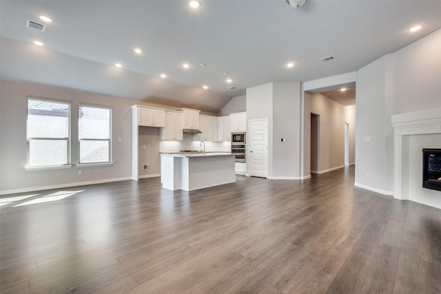 unfurnished living room with visible vents, recessed lighting, dark wood-type flooring, and a glass covered fireplace