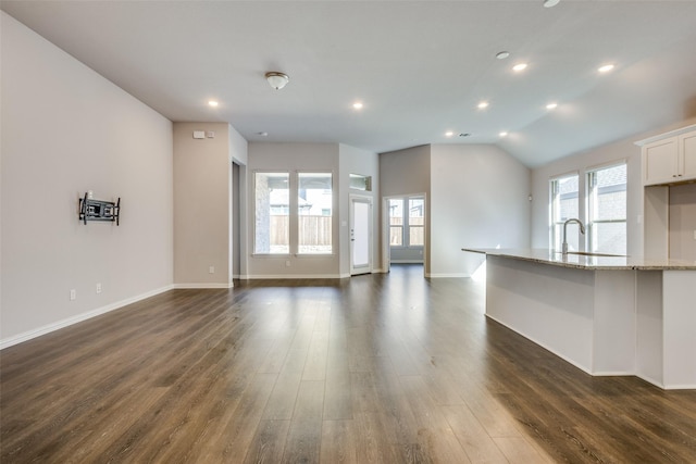 unfurnished living room featuring lofted ceiling, a sink, dark wood finished floors, recessed lighting, and baseboards