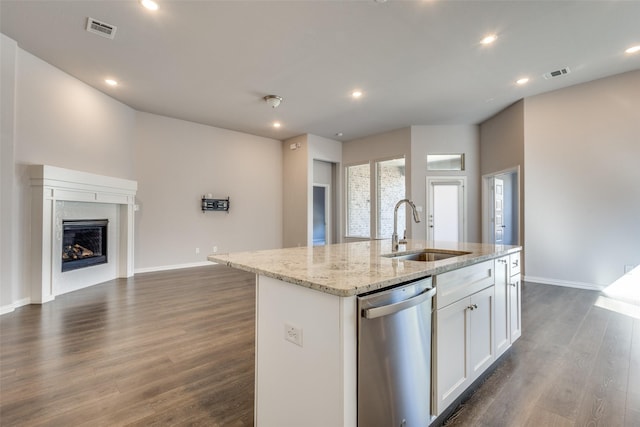 kitchen featuring visible vents, dark wood finished floors, a center island with sink, dishwasher, and a sink