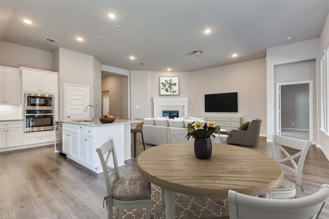 dining room featuring recessed lighting, baseboards, a glass covered fireplace, and dark wood finished floors