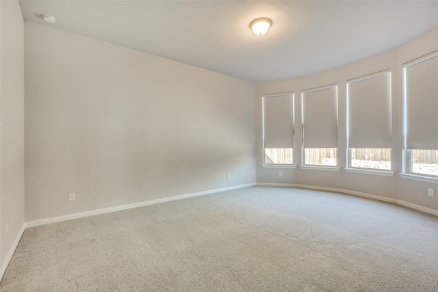 unfurnished room with carpet flooring and baseboards