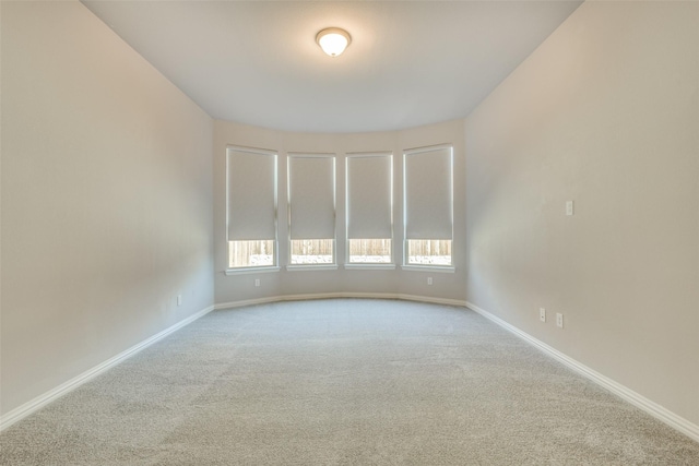 empty room featuring carpet and baseboards