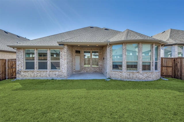 rear view of property featuring brick siding, a yard, and a fenced backyard