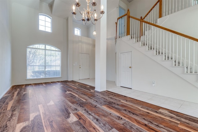 foyer featuring stairs, a high ceiling, a notable chandelier, and wood-type flooring