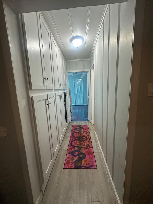 corridor with crown molding, attic access, and light wood finished floors