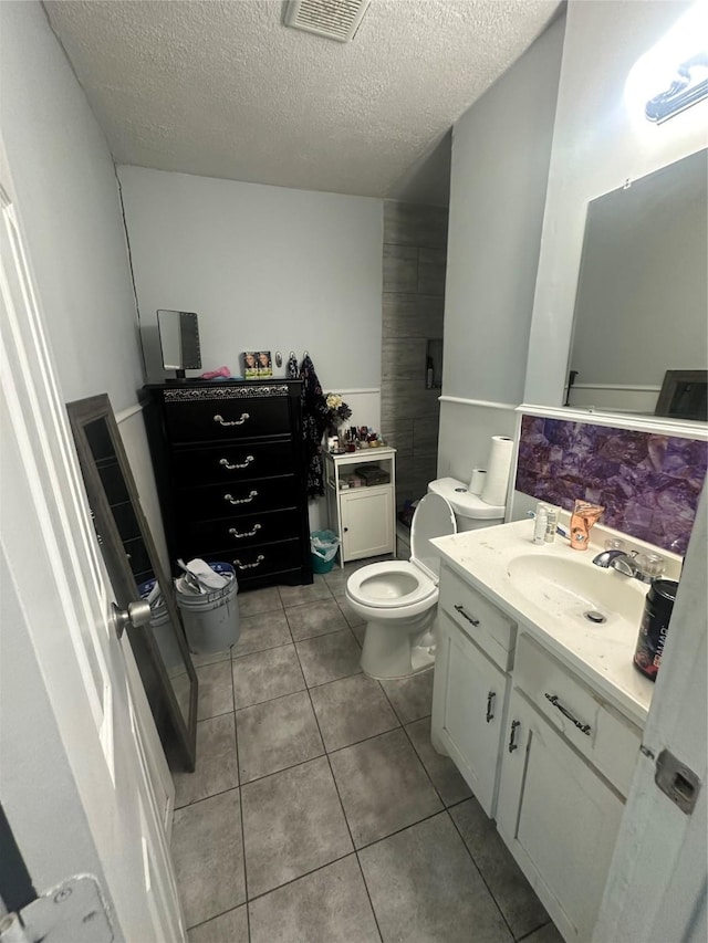 bathroom featuring tile patterned floors, visible vents, toilet, a textured ceiling, and vanity