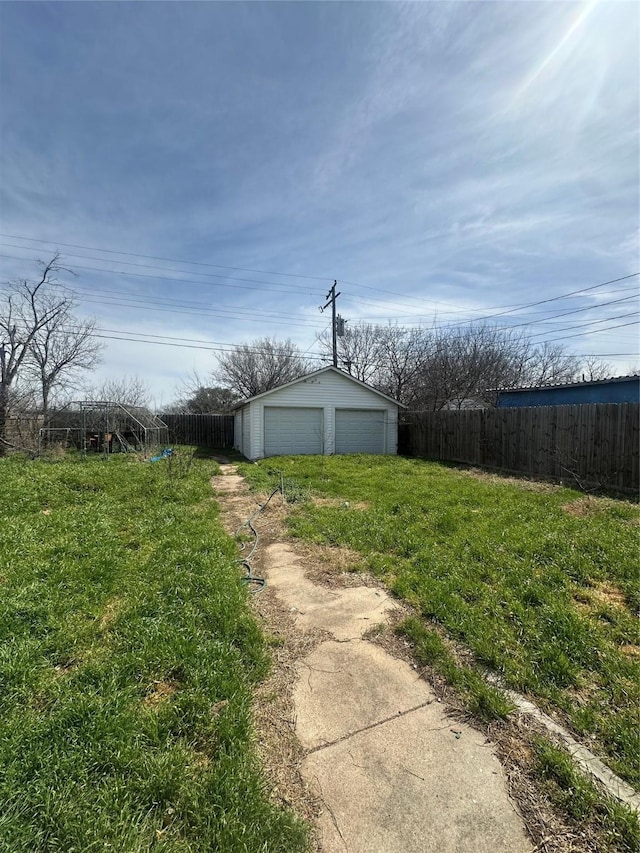 view of yard with an outdoor structure, fence, and a garage