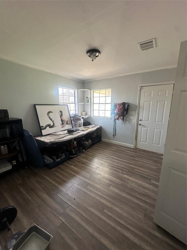 bedroom with visible vents, crown molding, baseboards, and wood finished floors