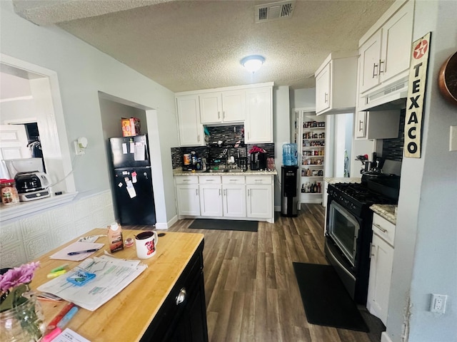 kitchen featuring range with gas stovetop, visible vents, dark wood finished floors, freestanding refrigerator, and white cabinetry