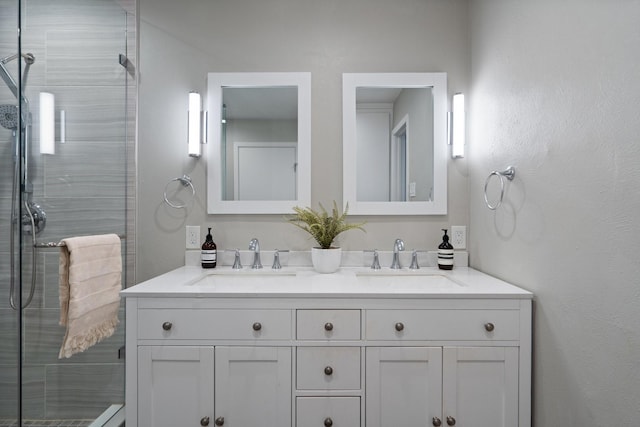 bathroom with double vanity, a shower stall, and a sink