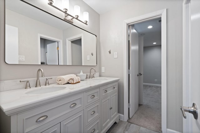 bathroom featuring double vanity, baseboards, and a sink