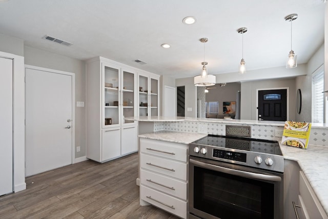 kitchen with visible vents, glass insert cabinets, stainless steel electric stove, wood finished floors, and white cabinetry