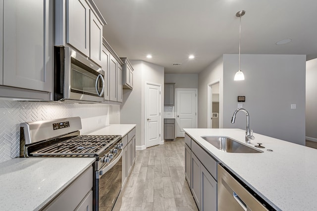 kitchen with a sink, appliances with stainless steel finishes, gray cabinetry, and light wood finished floors