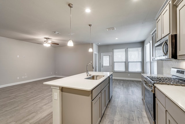 kitchen featuring a sink, appliances with stainless steel finishes, gray cabinetry, and light wood finished floors