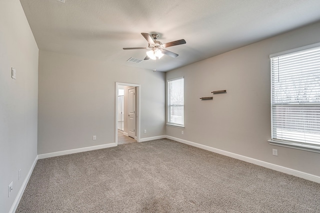 empty room featuring light carpet, visible vents, baseboards, and a ceiling fan