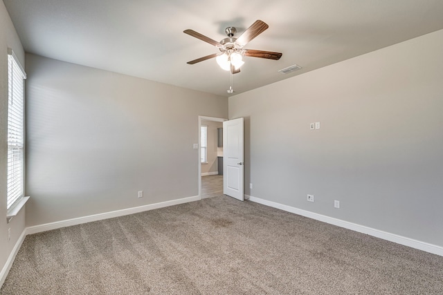 carpeted empty room with visible vents, baseboards, and ceiling fan