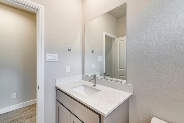 bathroom with baseboards, wood finished floors, and vanity