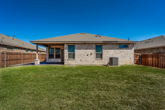 back of property with cooling unit, a lawn, a fenced backyard, and brick siding