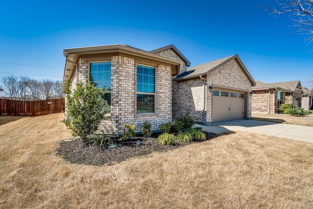 view of front of property with driveway, fence, a front yard, an attached garage, and brick siding